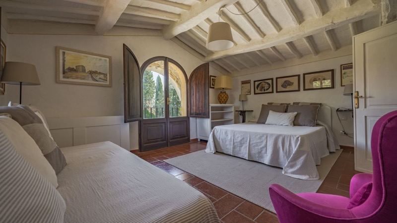 Bedroom with the fuchsia armchair and arched door
