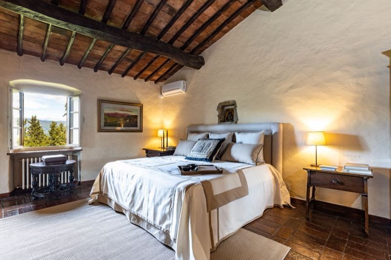 Bedroom with exposed beams and the window onto the trees