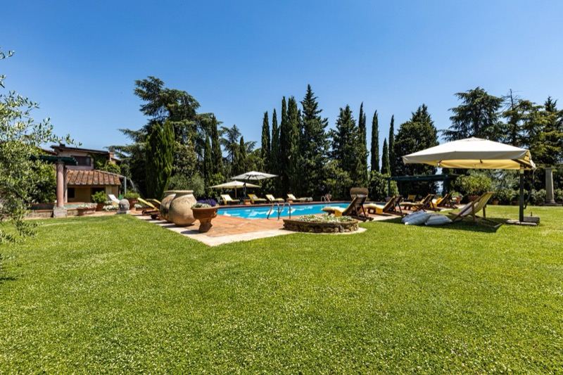The lawn around the pool with the pool house and terracotta jars