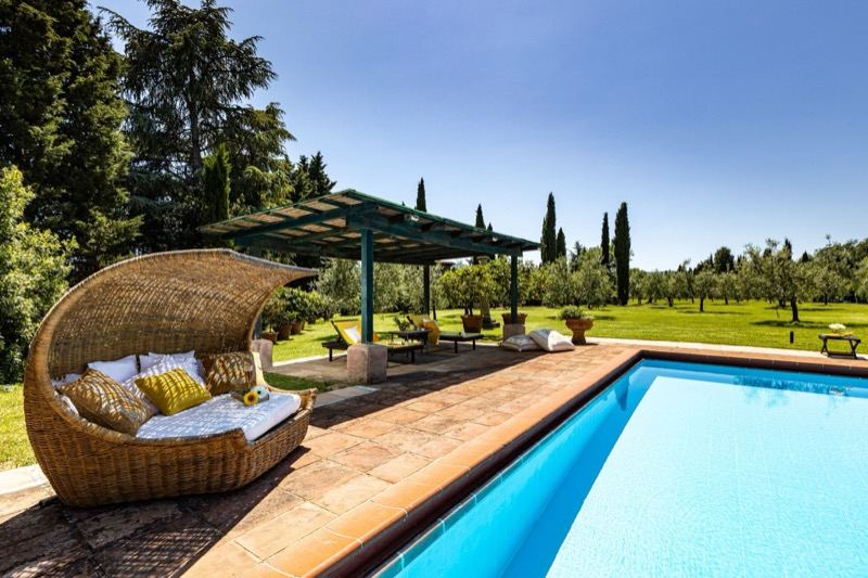 The wicker chair under the pergola by the pool