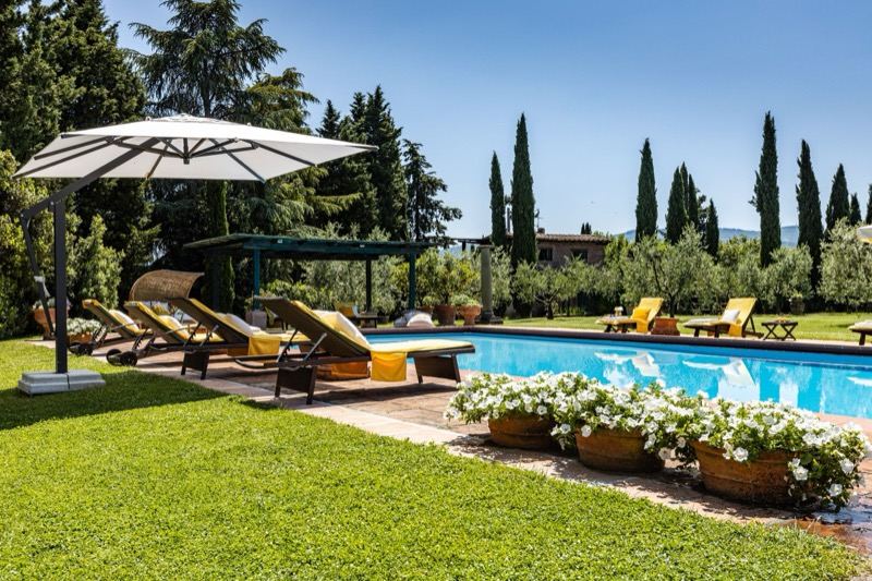 The pool with parasol, loungers and cypresses