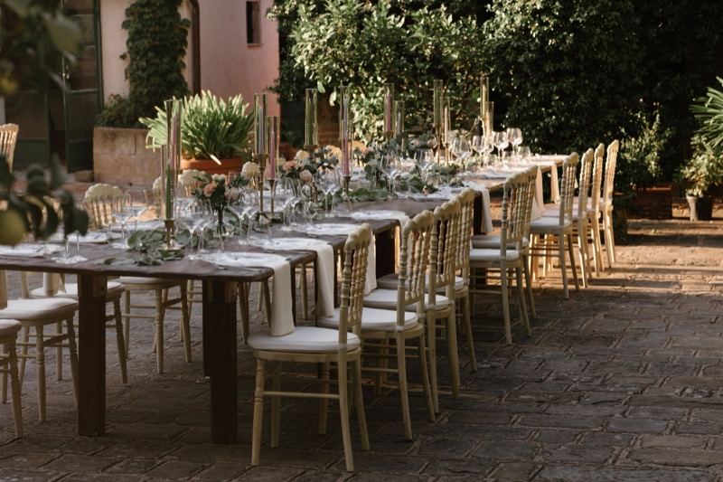 Tables and gilded chairs in the courtyard under the trees