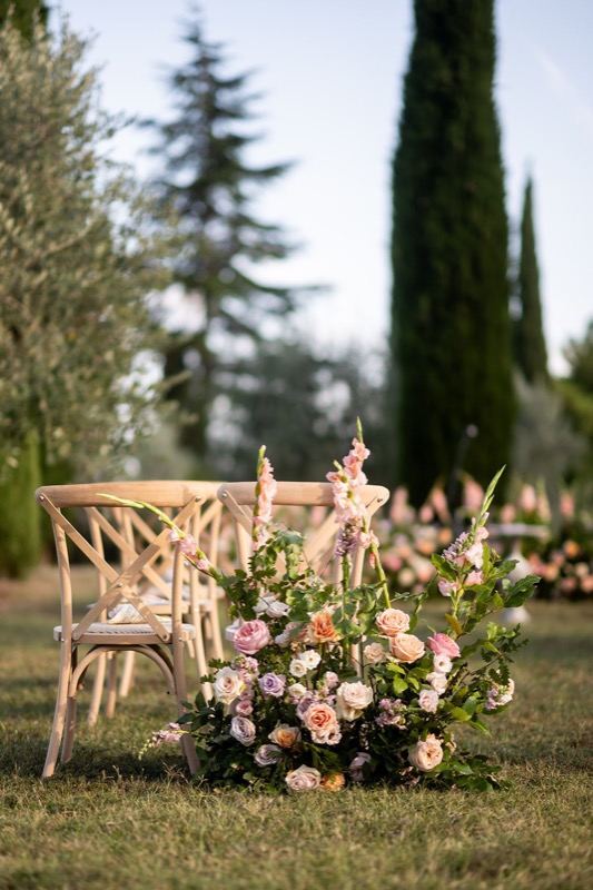 Wooden chairs and a rose arrangement among the cypresses