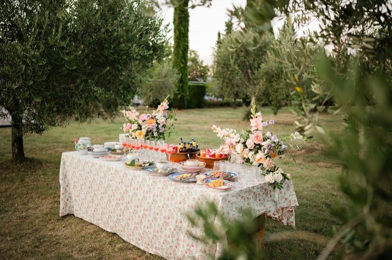 The buffet table with floral cloth under the olive trees