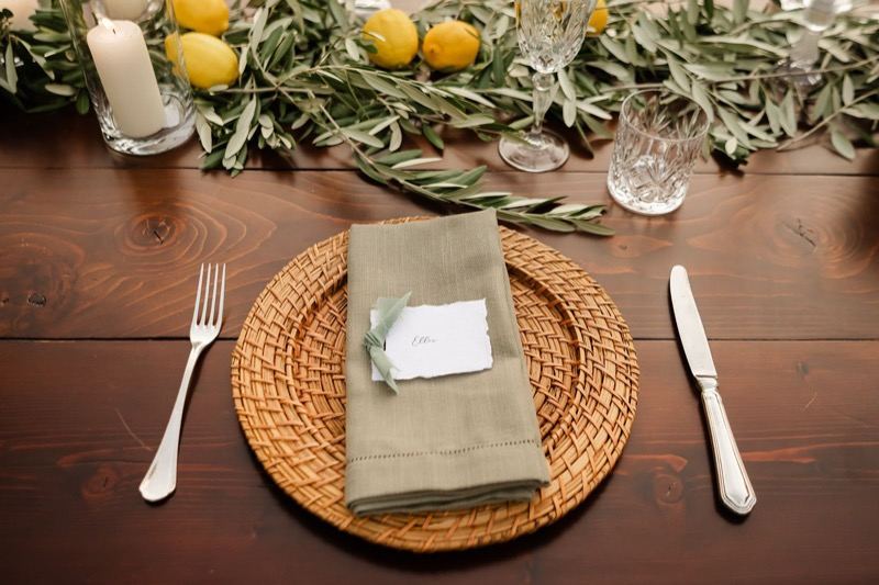 Place setting with wicker charger and olive-and-lemon garland