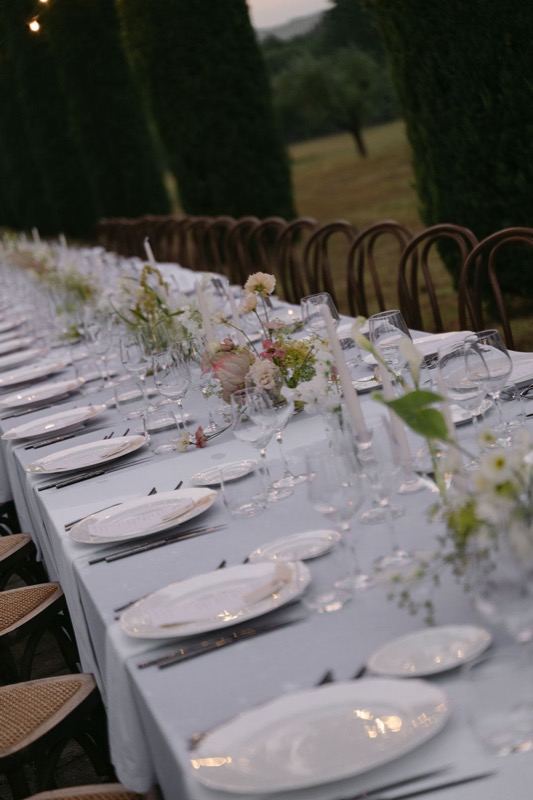 Long white table between the cypresses at dusk