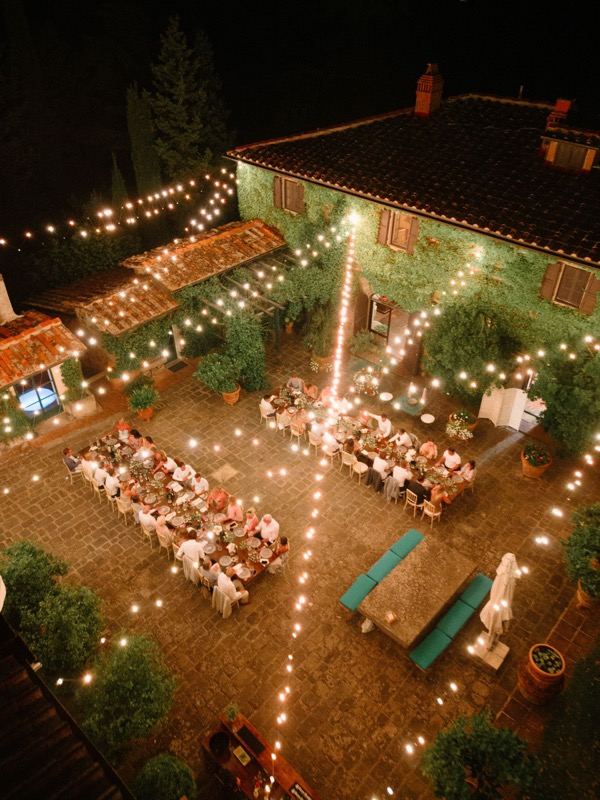 The courtyard dinner under string lights, seen from above at night