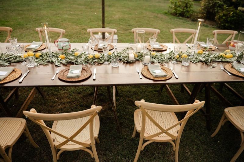 Wooden table with cross-back chairs, lemons and olive branches