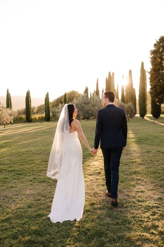The couple hand in hand on the lawn at sunset