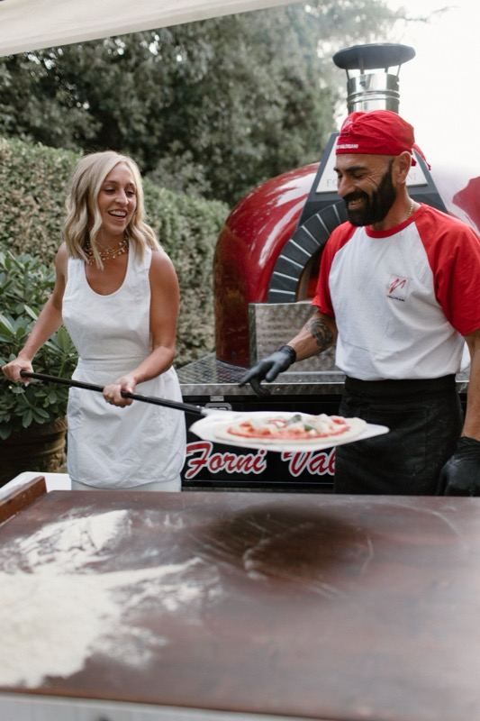 The bride at the wood-fired oven with the pizzaiolo