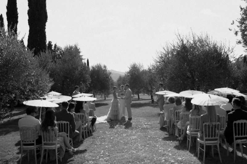 Guests with parasols at the ceremony, in black and white