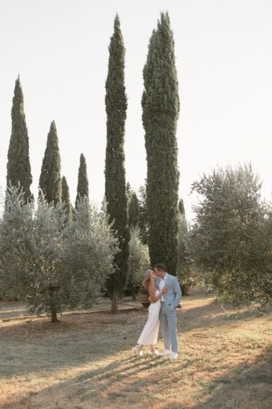 The couple's embrace among cypresses and olive trees