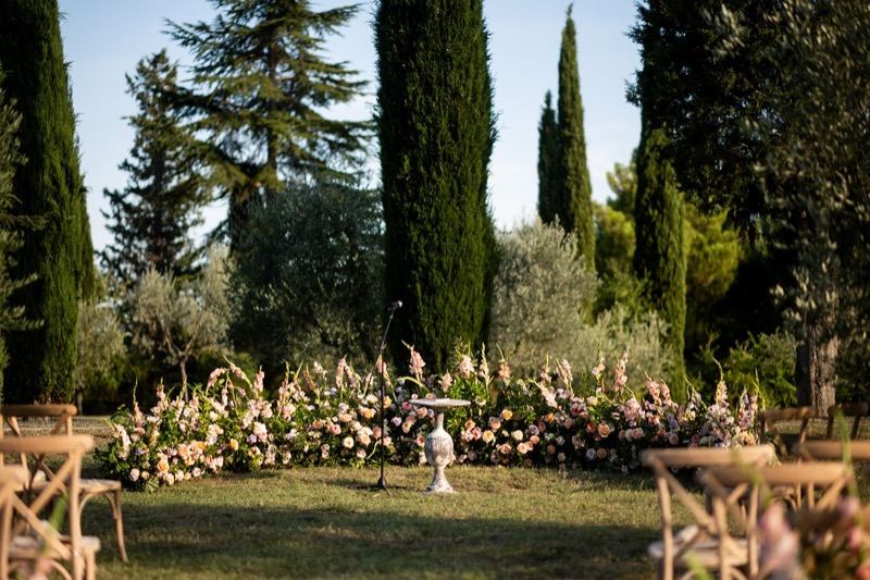 The floral altar among the cypresses, with wooden chairs