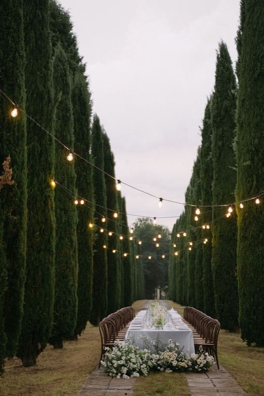 The lit cypress avenue with the table at the far end